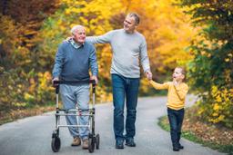 An older man, walking with a middle aged man and smaller boy on a trail in the woods
