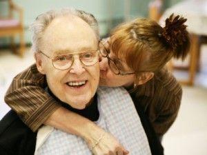 A woman kissing a man on the cheek while he smiles